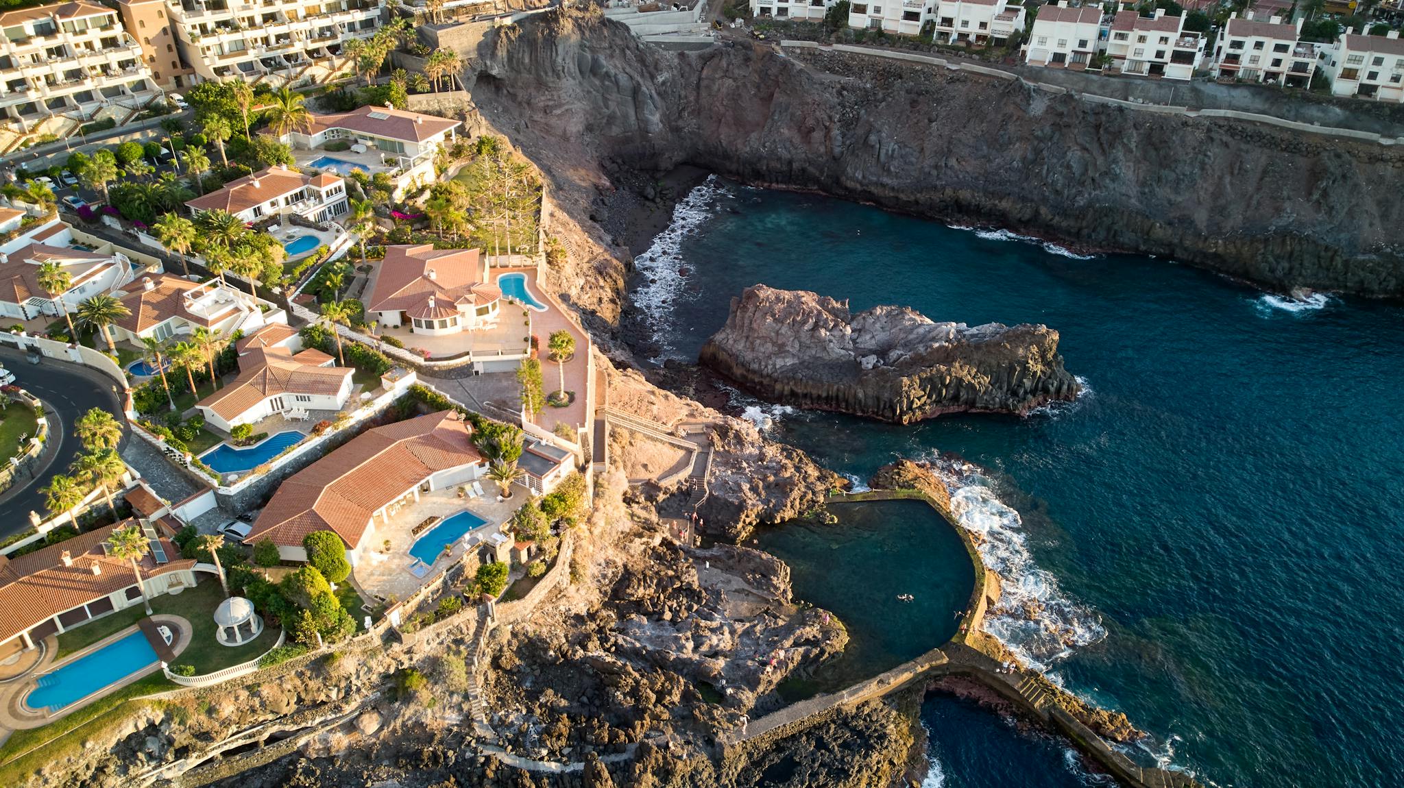 Stunning aerial view of luxury villas near the rocky shore of Santiago del Teide, Spain.